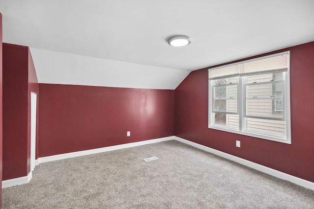 additional living space featuring carpet floors and vaulted ceiling