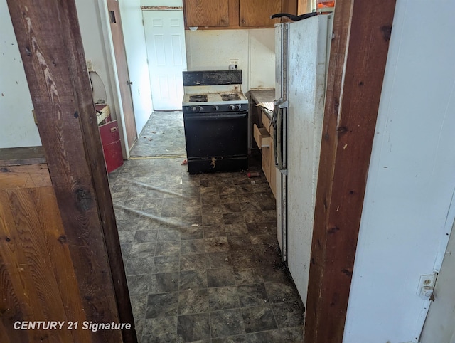 kitchen with range with gas cooktop, brown cabinetry, and freestanding refrigerator