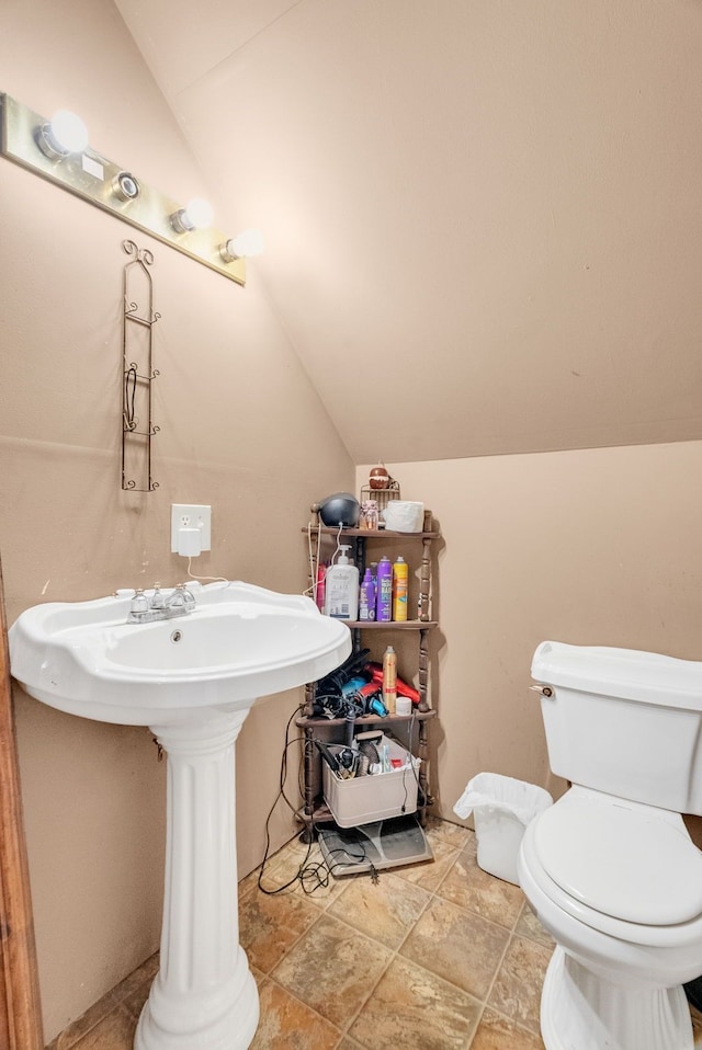 bathroom featuring sink, vaulted ceiling, and toilet