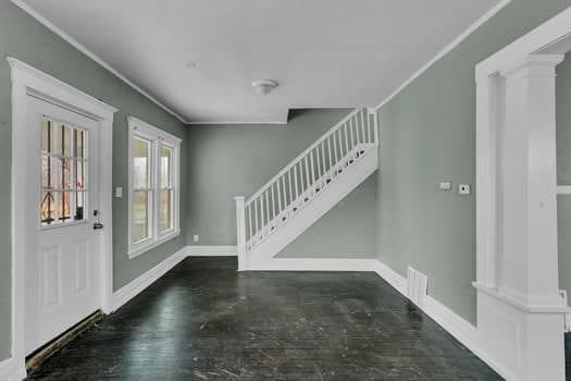 foyer entrance featuring dark wood-type flooring and ornamental molding