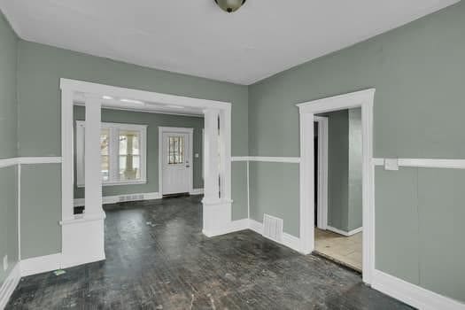 unfurnished room featuring dark hardwood / wood-style flooring and ornate columns