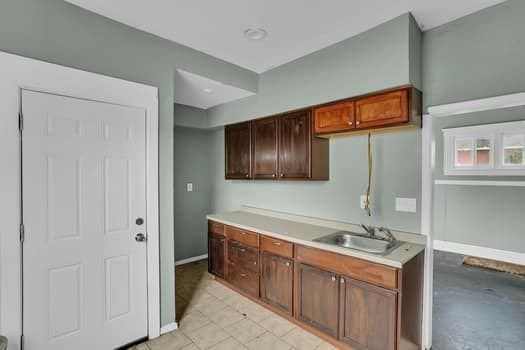 kitchen featuring baseboards, light countertops, and a sink