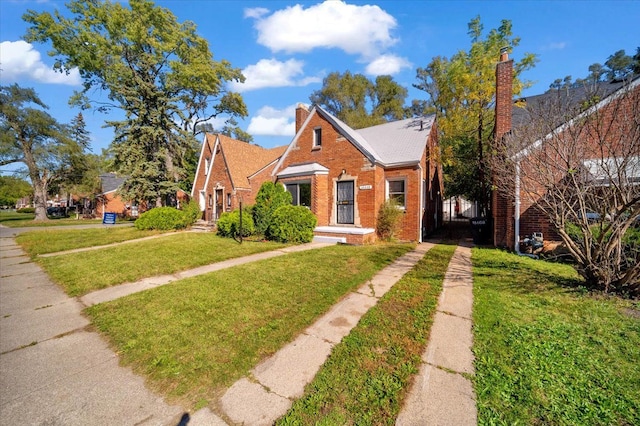 bungalow featuring brick siding, a chimney, and a front yard