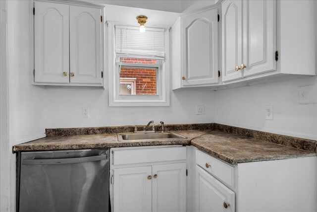 kitchen featuring dishwasher, dark countertops, a sink, and white cabinets