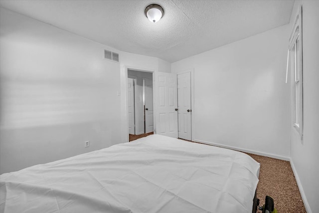 carpeted bedroom with baseboards, visible vents, and a textured ceiling