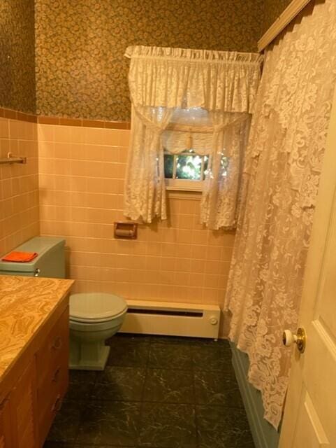 bathroom featuring tile walls, vanity, a baseboard radiator, and toilet