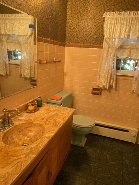 bathroom featuring vanity, a baseboard heating unit, tile walls, and toilet