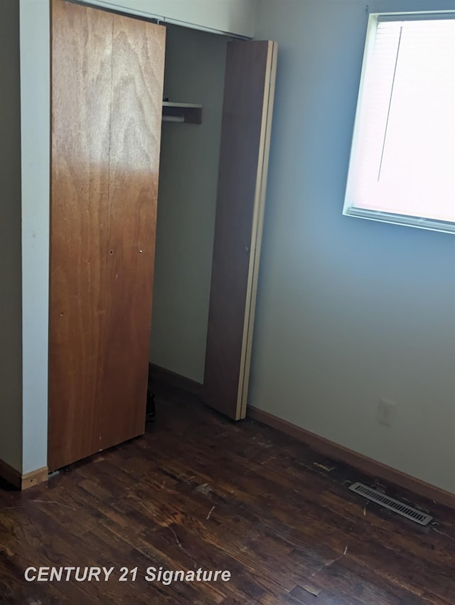 unfurnished bedroom with dark wood-type flooring and a closet