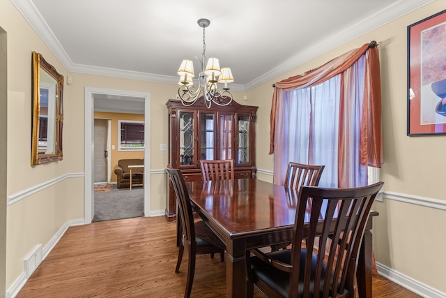 dining room featuring wood-type flooring, ornamental molding, and a chandelier