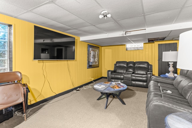 living room featuring carpet flooring, a paneled ceiling, and wood walls