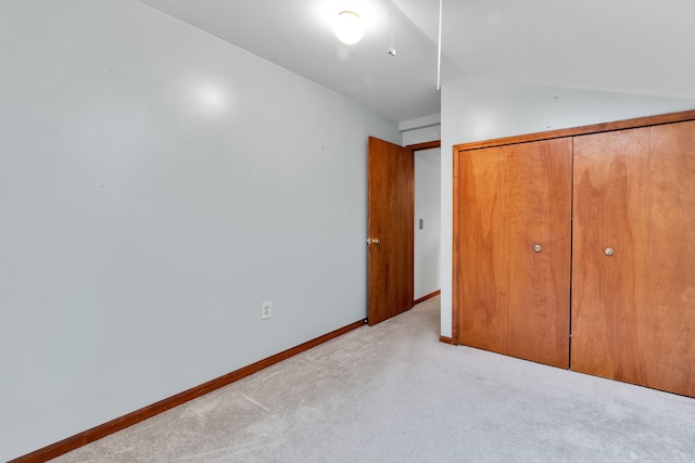 unfurnished bedroom with vaulted ceiling, light carpet, and a closet