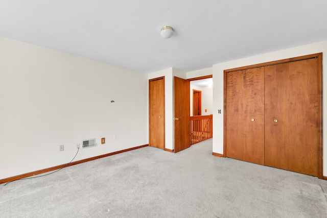 unfurnished bedroom featuring two closets and light colored carpet