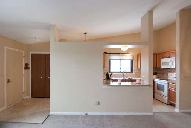 kitchen with pendant lighting, white appliances, lofted ceiling, and light carpet