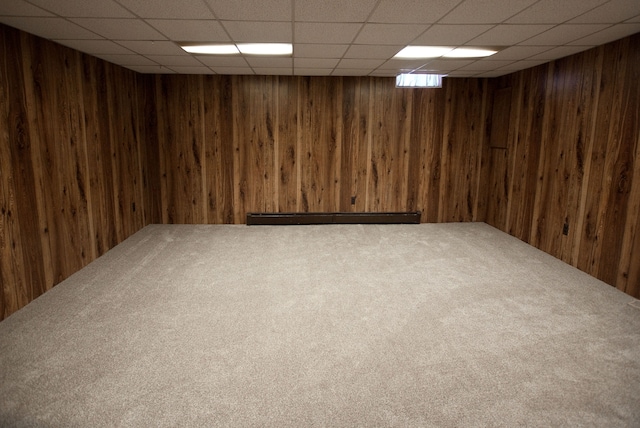 basement with carpet floors, wooden walls, and a drop ceiling