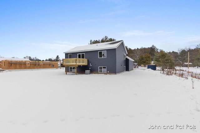 snow covered house featuring a wooden deck and central AC