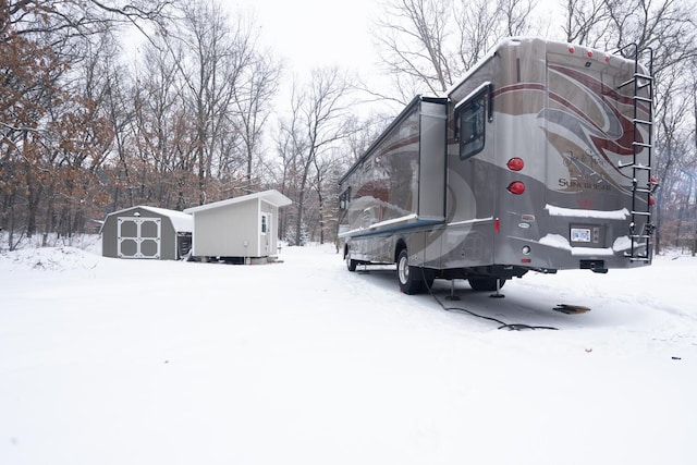 view of snowy exterior with a shed