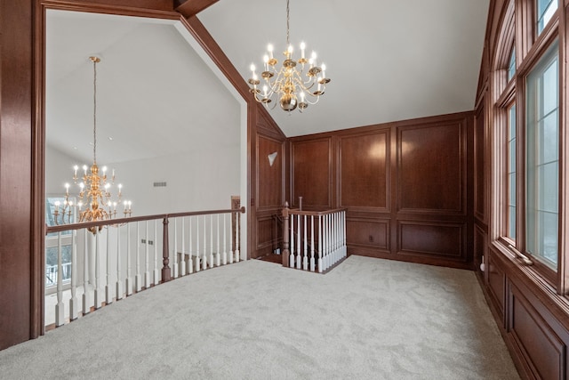 spare room featuring visible vents, light colored carpet, high vaulted ceiling, a decorative wall, and a notable chandelier