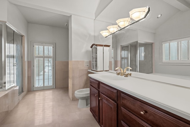 full bath featuring a wainscoted wall, vaulted ceiling, vanity, a bidet, and tile walls