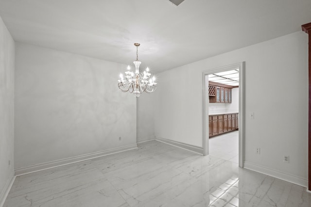 unfurnished dining area featuring a chandelier, marble finish floor, and baseboards