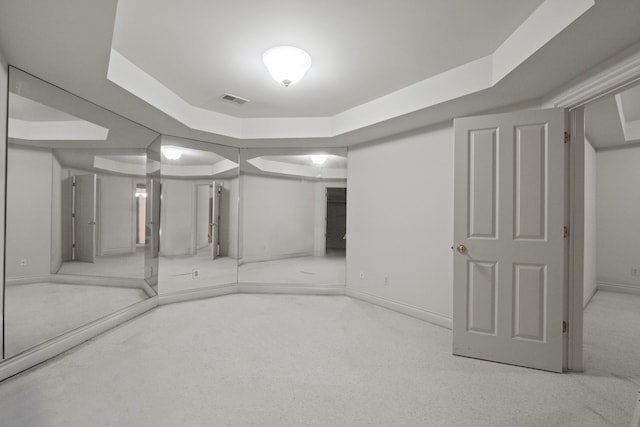 spare room featuring baseboards, visible vents, and a raised ceiling