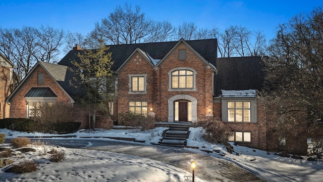 english style home featuring a chimney and brick siding