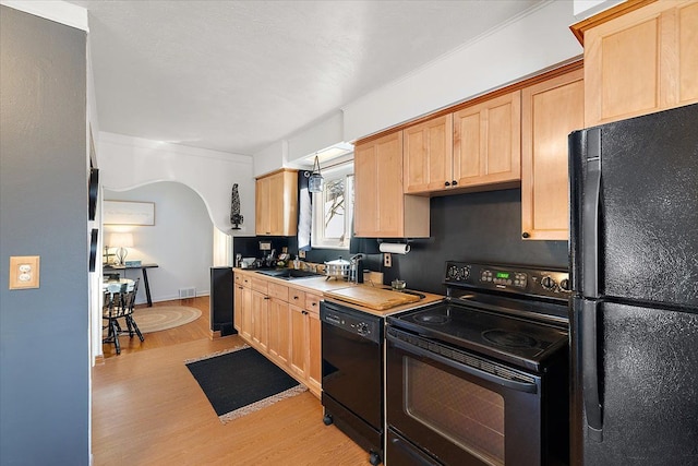 kitchen with sink, light hardwood / wood-style flooring, light brown cabinets, and black appliances