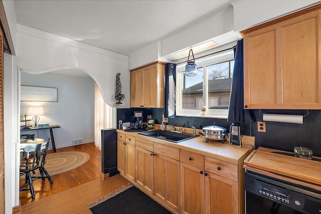 kitchen featuring crown molding, black dishwasher, sink, and light wood-type flooring