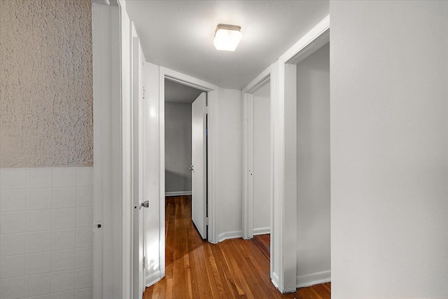 hallway with hardwood / wood-style floors and tile walls