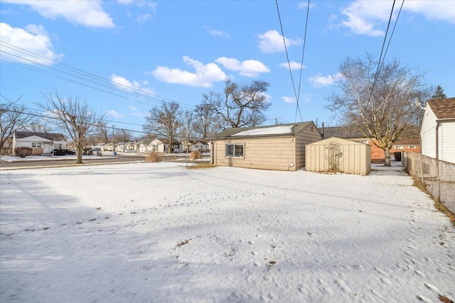 snowy yard featuring a storage unit