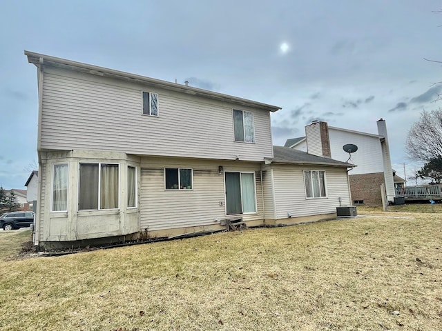 back of house with central AC unit and a lawn