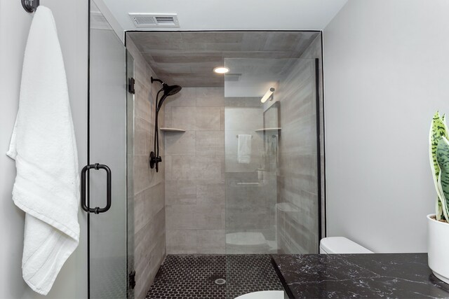 bathroom featuring a shower with door and toilet