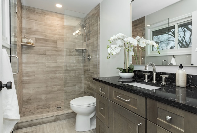 bathroom featuring vanity, a shower with shower door, and toilet