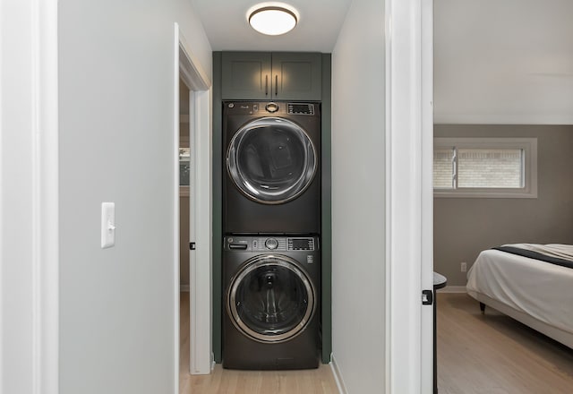 washroom with cabinets, stacked washer / dryer, and light hardwood / wood-style floors