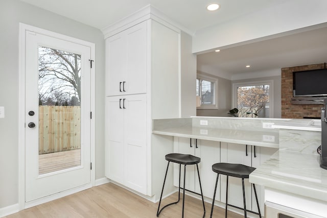 kitchen featuring light hardwood / wood-style floors, a breakfast bar, and white cabinets