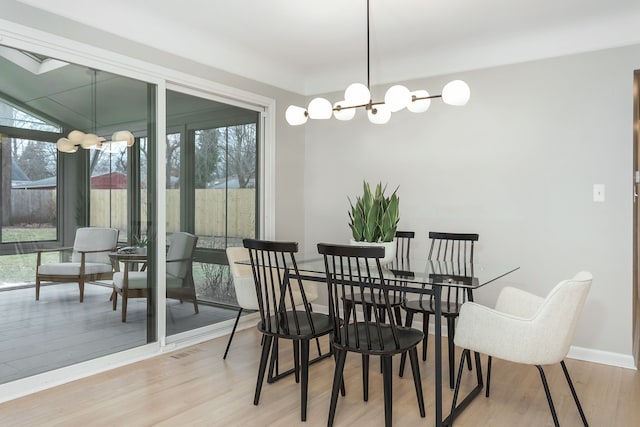 dining space featuring a notable chandelier, a healthy amount of sunlight, and light wood-type flooring