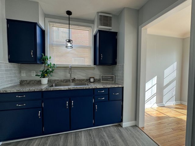 kitchen featuring hardwood / wood-style flooring, blue cabinetry, sink, and decorative light fixtures