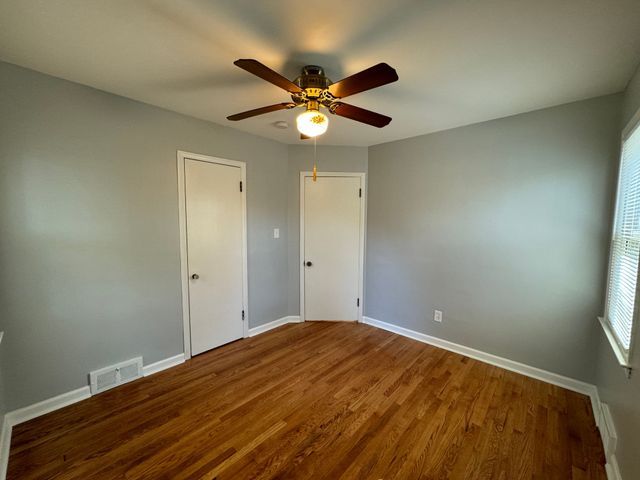 unfurnished bedroom with ceiling fan and wood-type flooring
