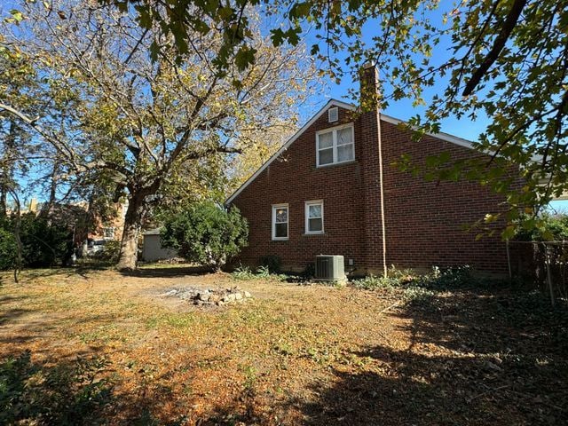 view of side of home featuring a lawn and central air condition unit