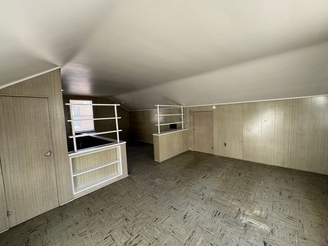 additional living space with vaulted ceiling and wooden walls
