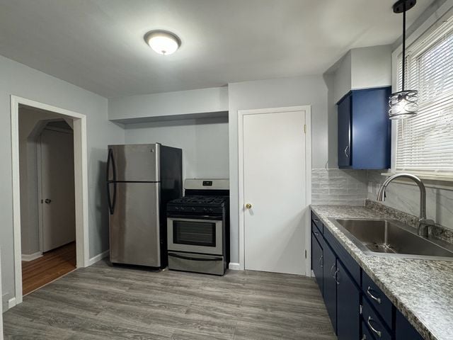 kitchen featuring stainless steel appliances, hardwood / wood-style flooring, sink, and blue cabinets