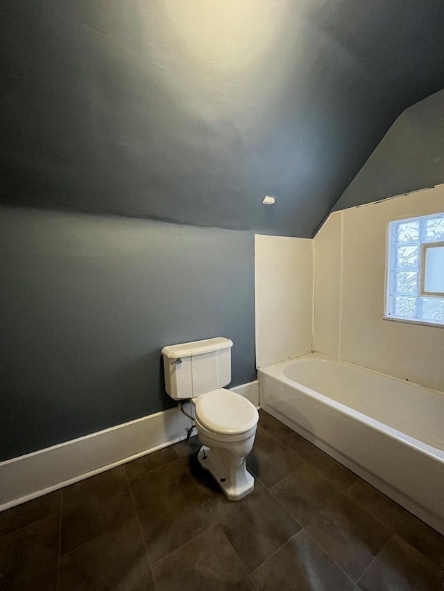 bathroom featuring tile patterned flooring, lofted ceiling, toilet, and a bathing tub