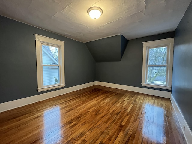 bonus room with a wealth of natural light, wood-type flooring, and vaulted ceiling