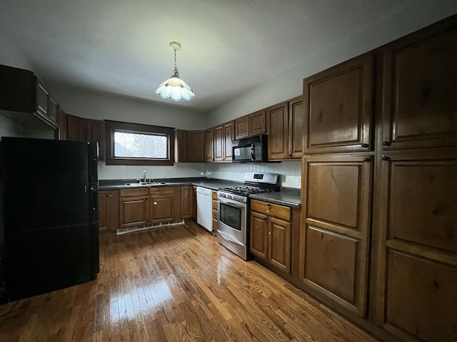 kitchen featuring decorative light fixtures, sink, dark hardwood / wood-style flooring, and black appliances