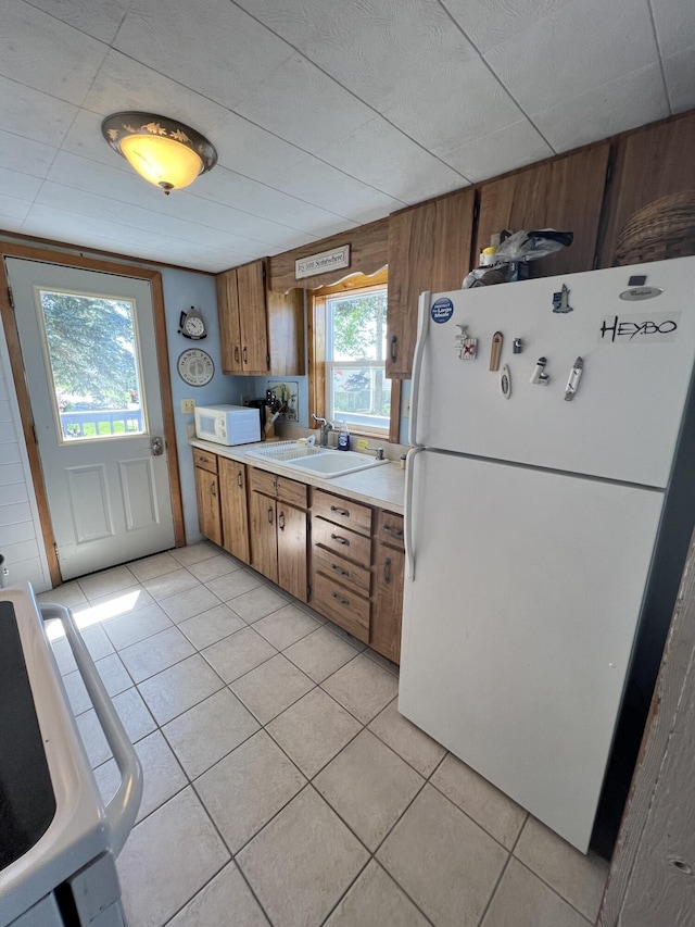 kitchen featuring sink, light tile patterned floors, white appliances, and wood walls