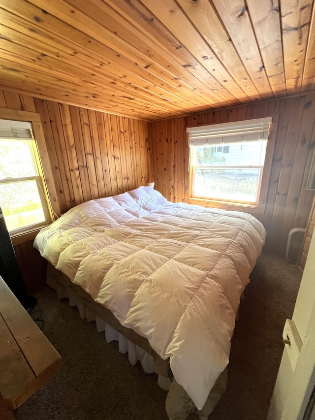 carpeted bedroom with multiple windows, wooden ceiling, and wood walls