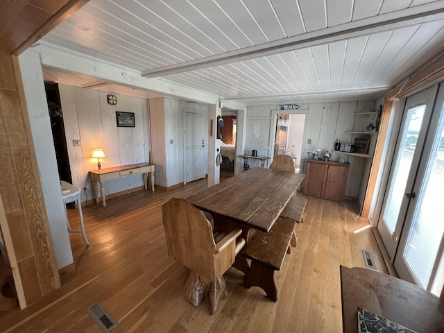 dining room with beamed ceiling, light hardwood / wood-style flooring, and wooden ceiling