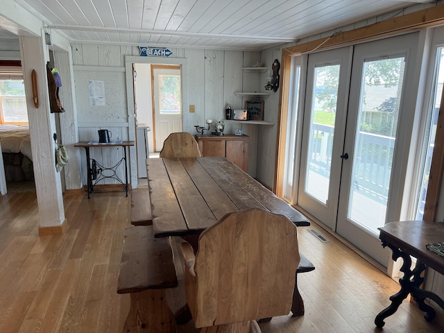 dining room featuring plenty of natural light, light hardwood / wood-style flooring, wood ceiling, and french doors