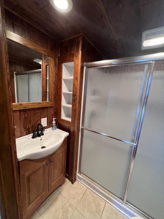 bathroom with vanity, wooden walls, a shower with shower door, and tile patterned flooring