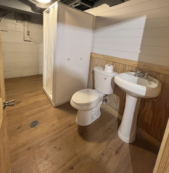 bathroom with wooden walls, wood-type flooring, and toilet