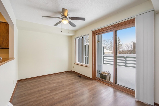 unfurnished room with ceiling fan, wood-type flooring, and a textured ceiling